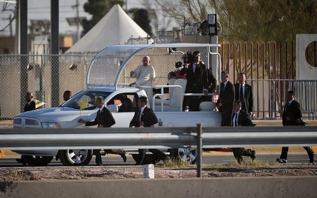 Security officers run beside the car of Pope Francis on the Mexico side of the border as he arrives to pray for those who died trying to cross the border at El Paso, Texas on February 17, 2016. (MARK RALSTON / AFP)