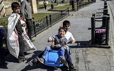 Syrian boys Hussein (L) Heisem (C) and Vissam (R) look at Turkish children enjoying on the street as they walk around collecting garbage on February 19, 2016 in the center of Gaziantep, southern Turkey. (AFP/BULENT KILIC)