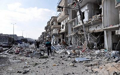Syrians inspect the damage at the site of a double car bomb attack in the Al-Zahraa neighborhood of the central Syrian city of Homs on February 21, 2016. (AFP/STRINGER)