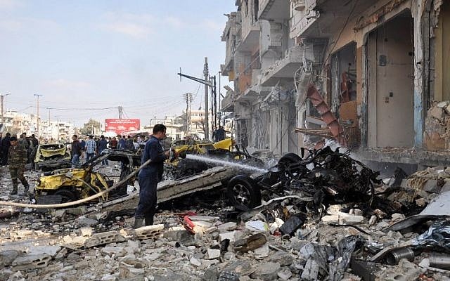 Syrian firefighters spray water on burning car at the site of a double car bomb attack in the Al-Zahraa neighborhood of the central Syrian city of Homs on February 21, 2016. (AFP/STRINGER) 