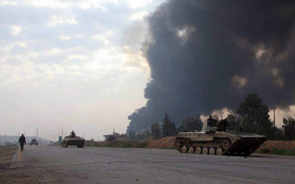Syrian government forces drive tanks near smoke billowing from Aleppo's thermal power plant after they took control of the area on the eastern outskirts Syria's northern embattled city from Islamic State (IS) group fighters on February 21, 2016. (AFP / GEORGE OURFALIAN)