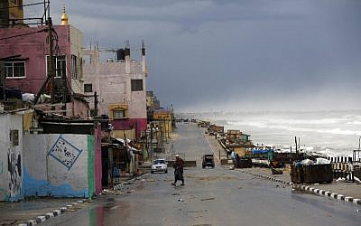 A Palestinian man walks along the beach next to al-Shatee refugee camp on a rainy day, in Gaza City, on February 22, 2016. AFP/MOHAMMED ABED