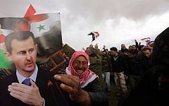 Syrian volunteers and their relatives wave the national flag and portraits of President Bashar Assad as they celebrate at the end of a paramilitary training conducted by the Syrian army on February 22, 2016. (AFP / LOUAI BESHARA)