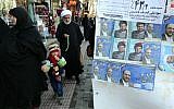 An Iranian cleric walks past electoral posters for upcoming parliamentary elections, near the Hazrat Fatimah Ma'sumeh mausoleum in Qom, on February 24, 2016. (AFP PHOTO / ATTA KENARE)