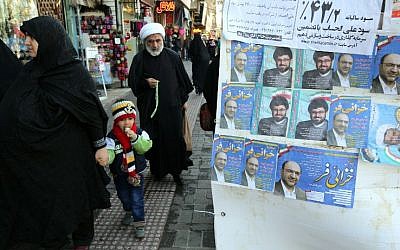 An Iranian cleric walks past electoral posters for upcoming parliamentary elections, near the Hazrat Fatimah Ma'sumeh mausoleum in Qom, on February 24, 2016. (AFP PHOTO / ATTA KENARE)