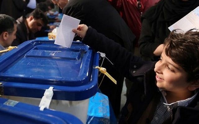 An Iranian boy casts his father ballot for both parliamentary elections and the Assembly of Experts at a polling station in Tehran on February 26, 2016. (AFP / ATTA KENARE) An Iranian boy casts his father ballot for both parliamentary elections and the Assembly of Experts at a polling station in Tehran on February 26, 2016. (AFP / ATTA KENARE)