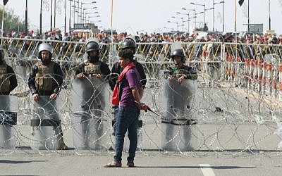 An Iraqi supporter of Shiite cleric Moqtada al-Sadr stands next to riot police during a demonstration in Baghdad's Tahrir Square on February 26, 2016, calling for governmental reform and elimination of corruption. (Ahmad al-Rubaye/AFP)