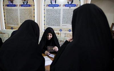 An Iranian election official registers voters for parliamentary and Assembly of Experts elections at a polling station at Massoumeh shrine in the holy city of Qom, on February 26, 2016. (AFP/BEHROUZ MEHRI)