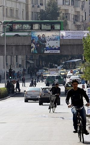 Syrians drive past government billboards in the capital Damascus, on February 27, 2016, as the first major ceasefire of the five-year war takes hold and an international task force prepares to begin monitoring the landmark truce. (AFP/LOUAI BESHARA)