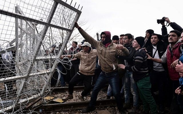 Migrants try to break through a border fence into Macedonia near the Greek village of Idomeni, on February 29 , 2016, where more than 7,000 people are stranded, as anger mounted over travel restrictions on migrants. (AFP / LOUISA GOULIAMAKI) Migrants try to break through a border fence into Macedonia near the Greek village of Idomeni, on February 29 , 2016, where more than 7,000 people are stranded, as anger mounted over travel restrictions on migrants. (AFP / LOUISA GOULIAMAKI)