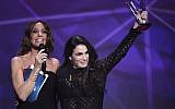 Israeli-French singer-songwriter Yael Naim (R), flanked by French TV host and Master of Ceremony Virginie Guilhaume (L) gestures after receiving the female artist award during the 31st Victoires de la Musique, the annual French music awards ceremony, on February 12, 2016 at the Zenith concert hall in Paris. (Bertrand Guay/AFP)