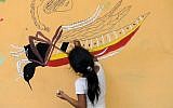 A girl paints a mural that educates people about a mosquito control project in the village of San Diego, in La Libertad, Salvador, on February 4, 2016.(AFP PHOTO/MARVIN RECINOS)
