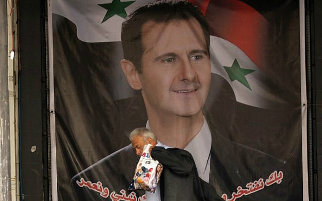 A Syrian man walks past a poster bearing a portrait of Syrian President Bashar Assad in the capital Damascus on February 23, 2016. (AFP/Louai Beshara) A Syrian man walks past a poster bearing a portrait of Syrian President Bashar Assad in the capital Damascus on February 23, 2016. (AFP/Louai Beshara)