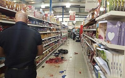 An Israel Police officer documents evidence at the scene of a stabbing attack at the Rami Levy supermarket in the Sha'ar Binyamin industrial park, north of Jerusalem, on February 18, 2016. (Israel Police)