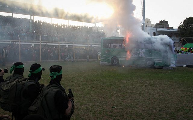 Palestinian militants of the Izz ad-Din al-Qassam, the armed wing of Hamas, burn a fake Israeli bus during an anti-Israel rally in the southern Gaza Strip city of Rafah on February 26, 2016. (Abed Rahim Khatib/Flash90)