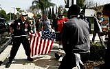 Illustrative: A Ku Klux Klansman, left, uses an American flag to fend off angry counter protesters after members of the KKK tried to start a 'White Lives Matter' rally at Pearson Park in Anaheim, California, on Saturday, Feb. 27, 2016. (Luis Sinco/Los Angeles Times via AP)