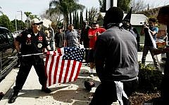 Illustrative: A Ku Klux Klansman, left, uses an American flag to fend off angry counter protesters after members of the KKK tried to start a 'White Lives Matter' rally at Pearson Park in Anaheim, California, on Saturday, Feb. 27, 2016. (Luis Sinco/Los Angeles Times via AP)