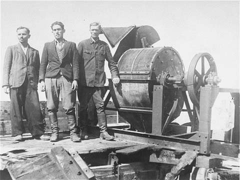 Jewish prisoners forced to work for a Sonderkommando 1005 unit pose next to a bone crushing machine in the Janowska concentration camp (ushmm.org via wikipedia)