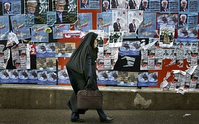 An Iranian woman walks past electoral posters of parliamentary election candidates on a sidewalk in downtown Tehran, Iran, Wednesday, Feb. 24, 2016. (AP Photo/Vahid Salemi)