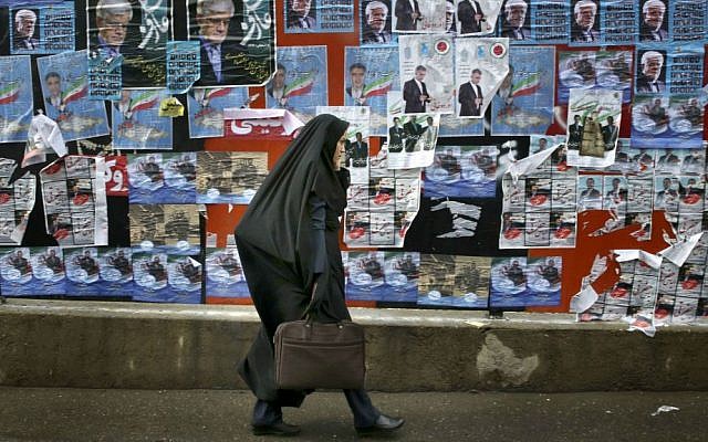An Iranian woman walks past electoral posters of parliamentary election candidates on a sidewalk in downtown Tehran, Iran, Wednesday, Feb. 24, 2016. (AP Photo/Vahid Salemi)