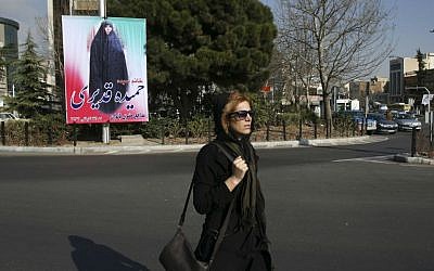 An Iranian woman walks in front of an electoral banner of Hamideh Ghadiri, a candidate in parliamentary elections in Vanak square in northern Tehran, Iran, Thursday, Feb. 25, 2016. The banner reads in Persian: "Hamideh Ghadiri - defender of women's rights." (AP Photo/Vahid Salemi)