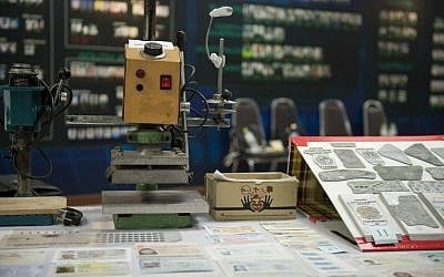 A presser, counterfeit passport printing plates and fake passports are displayed at the immigration bureau in Bangkok on February 10, 2016. (NICOLAS ASFOURI / AFP)