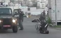 A Border Police officers pushes a Palestinian man out of his wheelchair in Hebron on February 14, 2016. (Screen capture: Shehab News Agency)