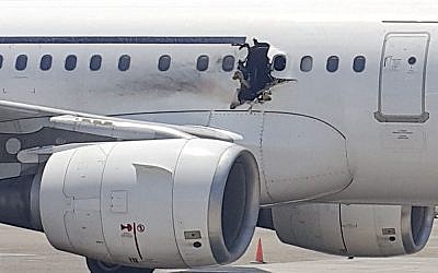In this Tuesday, Feb. 2, 2016 photo, a hole is photographed in a plane operated by Daallo Airlines as it sits on the runway of the airport in Mogadishu, Somalia. (AP Photo)