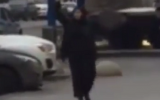 Still from a video showing a black-clad woman waving the severed head of a child in Moscow, ABC, February 29, 2016.