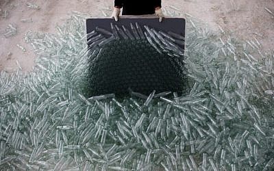 In this Jan. 27, 2016 photo, a worker breaks defective glass bottles to be recycled at the Phoenicia Glass Works Ltd. factory in the southern Israeli town of Yeruham. (AP Photo/Oded Balilty)