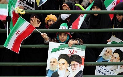 An Iranian girl holds a poster showing President Hassan Rouhani (left), previous leader Ayatollah Ruhollah Khomeini (center) and Supreme Leader Ayatollah Ali Khamenei (right) during celebrations in Tehran to mark the 37th anniversary of the Islamic Revolution, on February 11, 2016. (AFP/Atta Kenare)