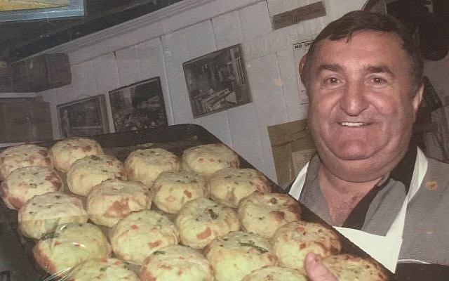 Alex Wolfson, seen here holding a tray of hot pastry, co-owns Yonah Schimmel’s Knish Bakery with his daughter, Ellen Anistratov. The pair are descendants of the original owner, and the business is one of the few ongoing Jewish landmarks in New York's Lower East Side. (courtesy Ellen Anistratov)