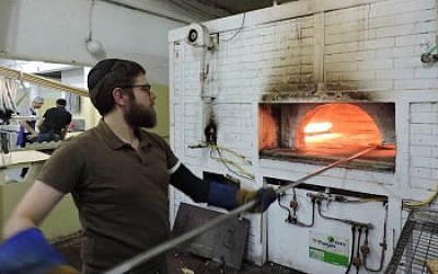 A man baking matzah in a brick oven in Kfar Chabad, a village that provides ritual materials to Chabad emissaries across Israel. (Ben Sales)