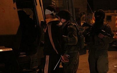 Illustrative. Soldiers load a Palestinian into the back of a military vehicle in Qalqilya on January 14, 2016. (Judah Ari Gross/Times of Israel)