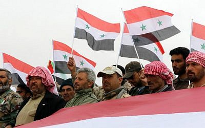 Syrian volunteers and their relatives wave the national flag and portraits of President Bashar al-Assad as they celebrate at the end of a paramilitary training conducted by the Syrian army in al-Qtaifeh on February 22, 2016. (LOUAI BESHARA / AFP)