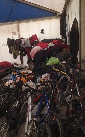 Piles of clothing and bikes inside the Sudanese tent in the Calais refugee camp, February 8, 2015. (Jenni Frazer/The Times of Israel)