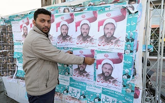 An Iranian man puts up election posters in the city of Qom, some 130 kilometres south of the capital, February 24, 2016. (AFP/Atta Kenare)