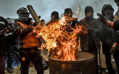 Migrants keep warm around a brasero as agents dismantle shacks on March 1, 2016 in the "Jungle" migrant camp in the French northern port city of Calais. (AFP / PHILIPPE HUGUEN)