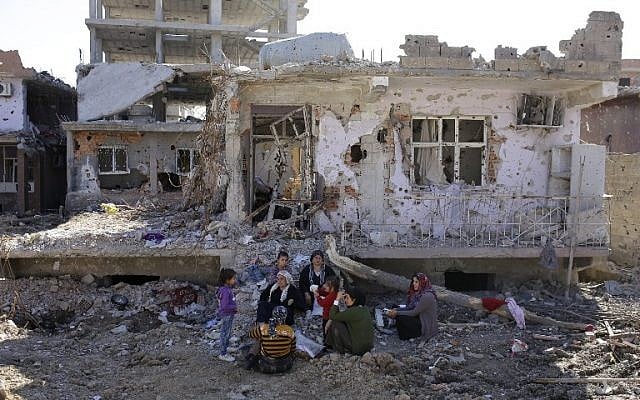 People wait in front of their damaged house following heavy fighting between government troops and Kurdish fighters, on March 2, 2016 in the southeastern Turkey Kurdish town of Cizre, near the border with Syria and Iraq. (AFP/Yasin Akgul)