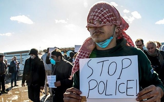 One of 12 migrants claiming to be from Iran protests with sewn lips and a poster reading 'Stop Police' against the dismantling of the southern part of the so-called 'Jungle' migrant camp in Calais, northern France, on March 4, 2016. (AFP/PHILIPPE HUGUEN) One of 12 migrants claiming to be from Iran protests with sewn lips and a poster reading 'Stop Police' against the dismantling of the southern part of the so-called 'Jungle' migrant camp in Calais, northern France, on March 4, 2016. (AFP/PHILIPPE HUGUEN)