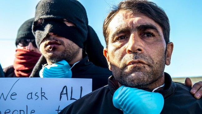Migrants claiming to be from Iran protest with sewn lips against the dismantling of the southern part of the so-called 'Jungle' migrant camp in Calais, northern France, on March 4, 2016. (AFP / PHILIPPE HUGUEN)