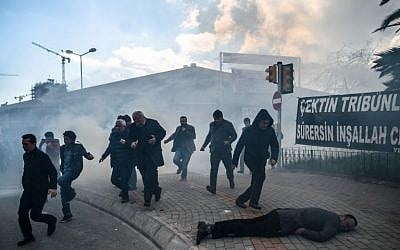 A man lies on the ground as others run as Turkish anti-riot police officers use tear gas to disperse supporters in front of the headquarters of the Turkish daily newspaper Zaman in Istanbul on March 5, 2016, after Turkish authorities seized the headquarters in a midnight raid. (AFP / OZAN KOSE) A man lies on the ground as others run as Turkish anti-riot police officers use tear gas to disperse supporters in front of the headquarters of the Turkish daily newspaper Zaman in Istanbul on March 5, 2016, after Turkish authorities seized the headquarters in a midnight raid. (AFP / OZAN KOSE)