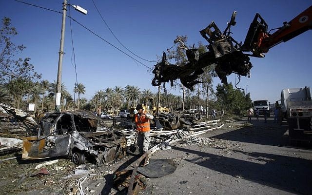 Iraqi emergency responders clear debris from the site of a truck bomb, that exploded at a crowded checkpoint, in the Iraqi city of Hilla, south of Baghdad, March 6, 2016. (AFP/HAIDAR HAMDANI)