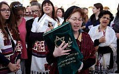 A member of the Women of the Wall wears a tallit (prayer shawl)  as she prays holding a Torah scroll at the Western Wall in Jerusalem on March 11, 2016 (AFP/GALI TIBBON)
