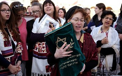 A member of the Women of the Wall wears a tallit (prayer shawl)  as she prays holding a Torah scroll at the Western Wall in Jerusalem on March 11, 2016 (AFP/GALI TIBBON)