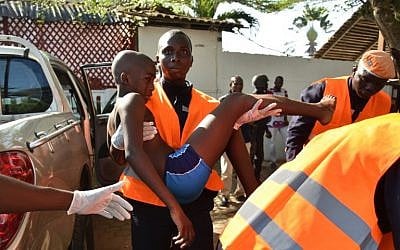 An emergency worker carries a young boy who was injured during an attack on the beach at the hotel Etoile du Sud in Grand Bassam, Ivory Coast, March 13, 2016. (AFP/Sia KAMBOU)