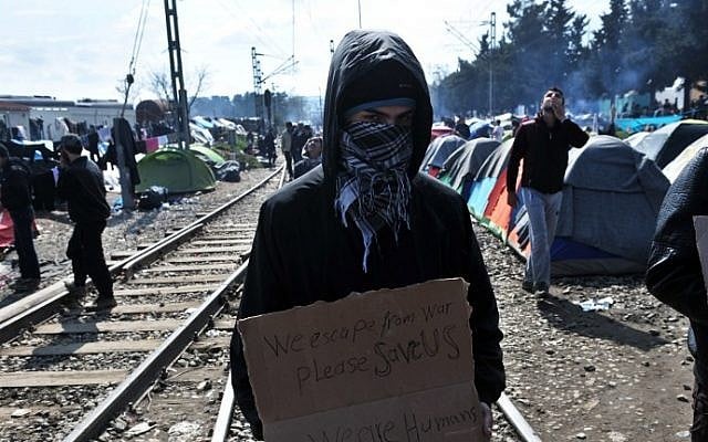 A migrant holds a placard reading "We escape from war, please save us, we are humans" in a makeshift camp at the Greek-Macedonian border, near the Greek village of Idomeni, on March 18, 2016. (Sakis Mitrolidis/AFP) A migrant holds a placard reading "We escape from war, please save us, we are humans" in a makeshift camp at the Greek-Macedonian border, near the Greek village of Idomeni, on March 18, 2016. (Sakis Mitrolidis/AFP)