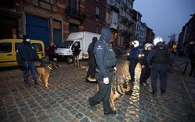 Police dog handlers stand guard the streets at Rue de la Carpe in Molenbeek-Saint-Jean in Brussels, early on March 19, 2016, a day after Belgian police arrested five people in counter-terror raids in Brussels, including Paris attacks suspect Salah Abdeslam and the family who sheltered him, prosecutors said. (AFP/Belga/Nicolas Maeterlinck)