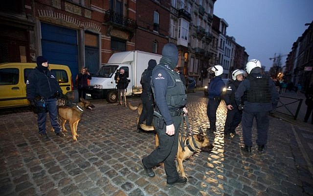 Police dog handlers stand guard the streets at Rue de la Carpe in Molenbeek-Saint-Jean in Brussels, on March 19, 2016, early morning. Belgian police arrested five people in counter-terror raids in Brussels on March 18, including Paris attacks suspect Salah Abdeslam and the family who sheltered him, prosecutors said. (AFP/Belga/Nicolas Maeterlinck)