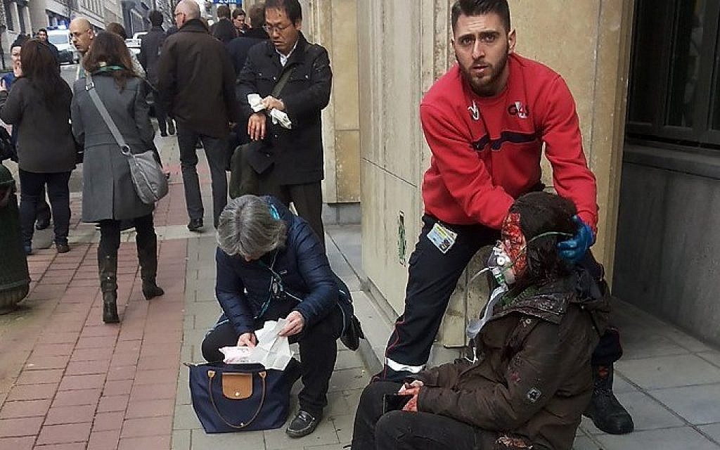 A private security guard helps a wounded women outside the Maalbeek metro station in Brussels on March 22, 2016 after a blast at this station located near the EU institutions. (AFP / Michael VILLA)